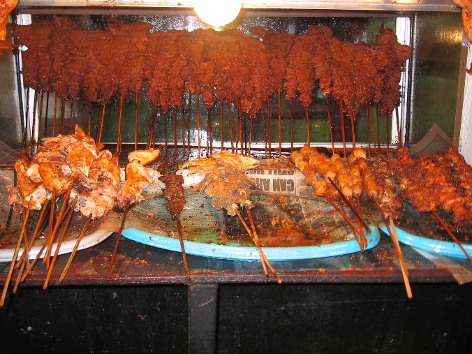 Suya skewers grilling at a Nigerian street-food stand